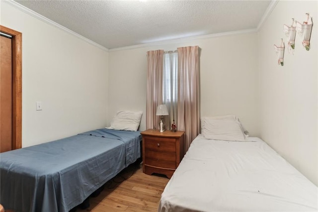 bedroom featuring light wood-type flooring, crown molding, and a textured ceiling