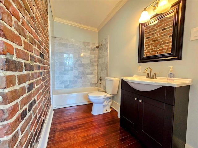 full bathroom with vanity, tiled shower / bath, hardwood / wood-style flooring, brick wall, and toilet