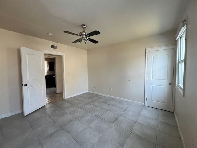 tiled empty room with ceiling fan and a wealth of natural light