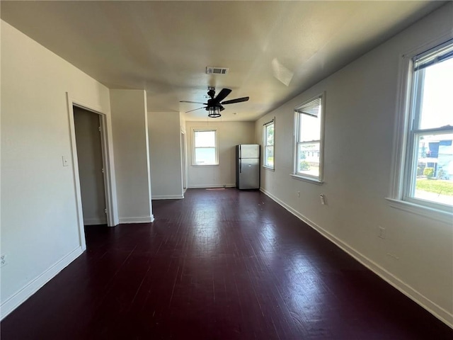 unfurnished room featuring dark wood-type flooring, ceiling fan, and plenty of natural light