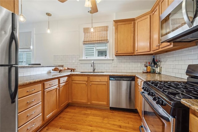 kitchen with light hardwood / wood-style flooring, stainless steel appliances, light stone counters, sink, and ceiling fan