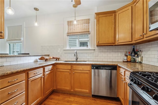 kitchen featuring backsplash, light wood-type flooring, light stone countertops, and appliances with stainless steel finishes