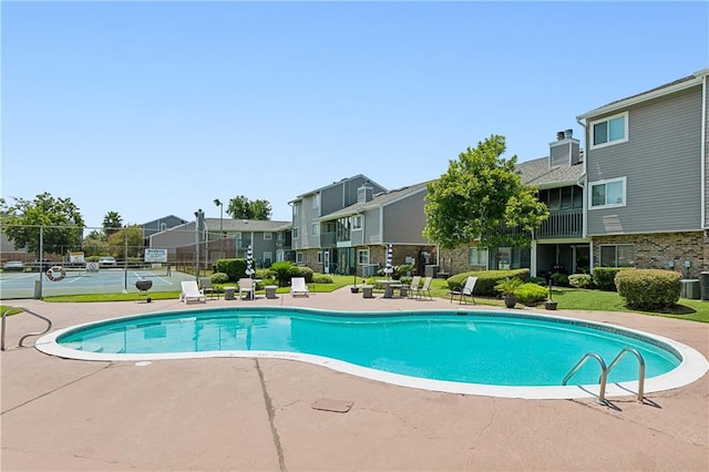 view of pool with tennis court and a patio area