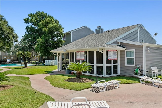 rear view of property featuring a fenced in pool, a yard, a patio, and a sunroom