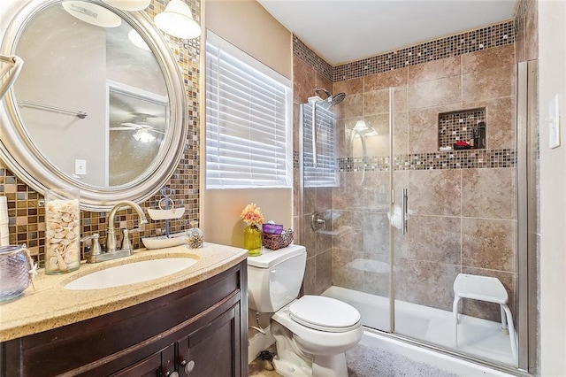 bathroom with tile walls, toilet, a shower with door, and vanity