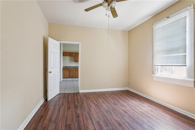 unfurnished room featuring ceiling fan, baseboards, and dark wood-style floors
