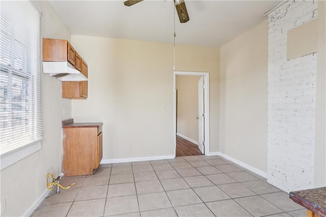 unfurnished dining area featuring light tile patterned floors, baseboards, and a ceiling fan
