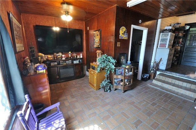 living room featuring wood ceiling, ceiling fan, and wooden walls