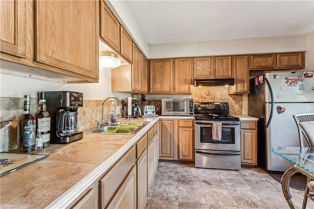 kitchen featuring appliances with stainless steel finishes, tile counters, decorative backsplash, and sink