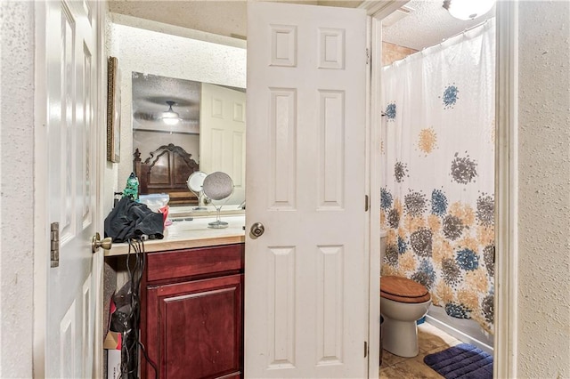 bathroom featuring tile patterned floors, toilet, a shower with curtain, vanity, and a textured ceiling