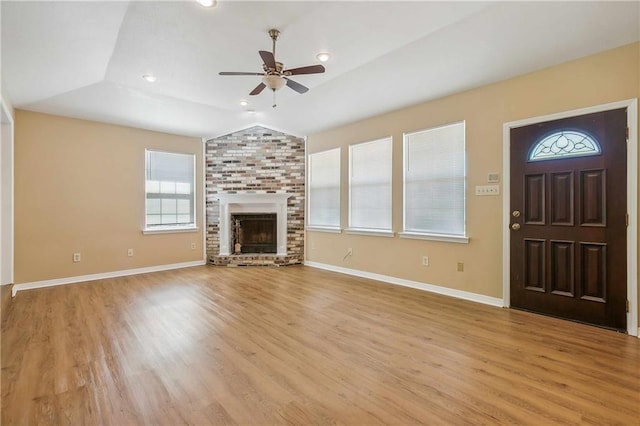 unfurnished living room with a brick fireplace, ceiling fan, lofted ceiling, and light hardwood / wood-style flooring