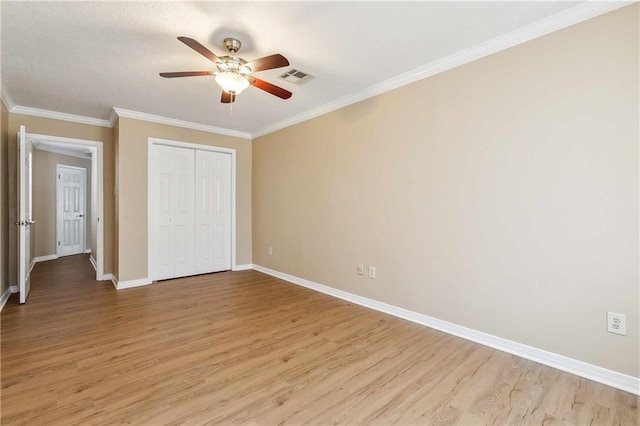 unfurnished bedroom featuring ceiling fan, light hardwood / wood-style floors, crown molding, and a closet