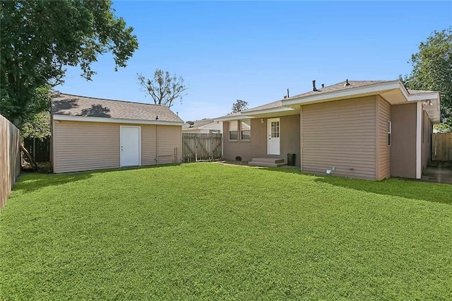 back of property with a yard and an outdoor structure