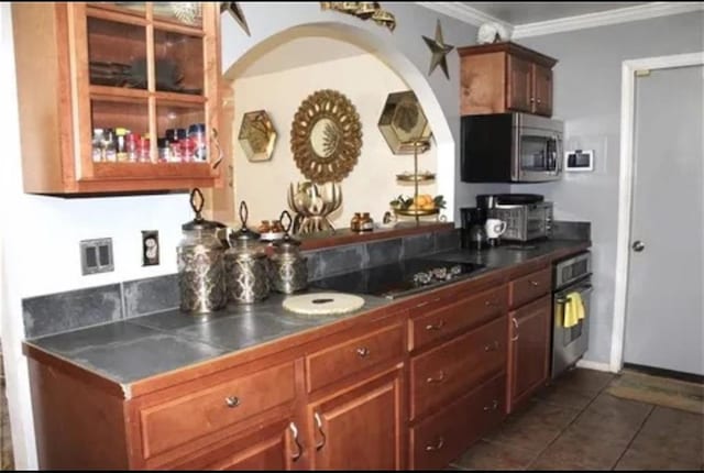 kitchen featuring dark tile patterned flooring, stainless steel appliances, and ornamental molding