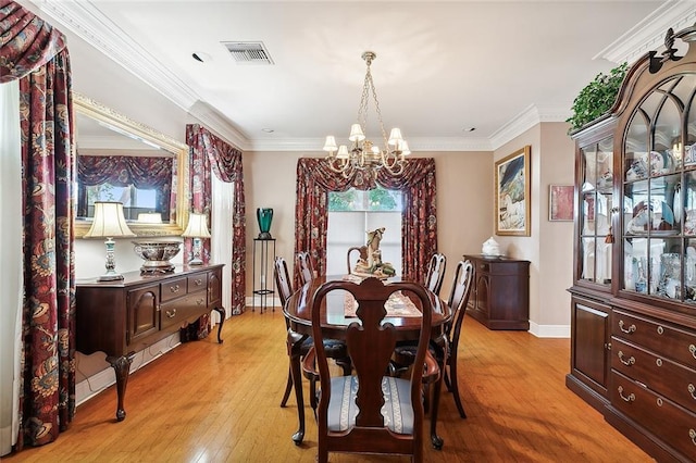 dining room featuring light wood-type flooring, a notable chandelier, and ornamental molding