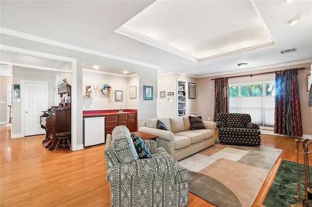 living room featuring crown molding, a raised ceiling, and light hardwood / wood-style floors