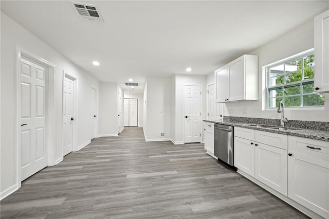 kitchen with white cabinetry, sink, dishwasher, light stone counters, and light hardwood / wood-style floors