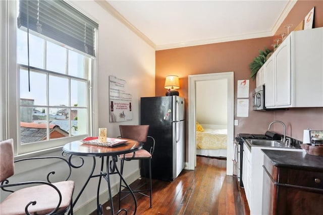 kitchen with crown molding, white cabinetry, dark hardwood / wood-style flooring, and stainless steel appliances