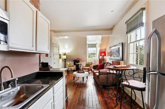 kitchen with white cabinets, dark hardwood / wood-style flooring, stainless steel appliances, ornamental molding, and sink