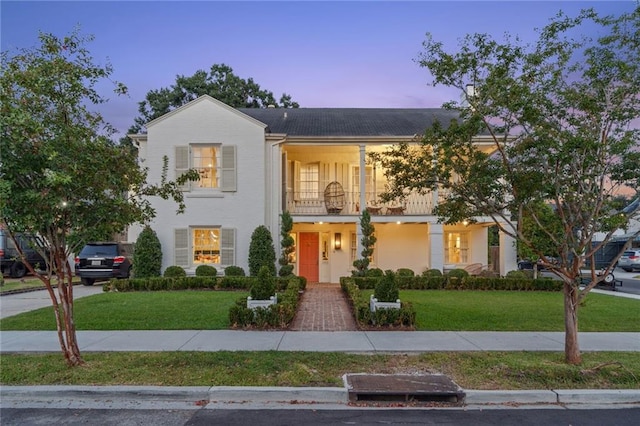 view of front of property with a balcony and a yard