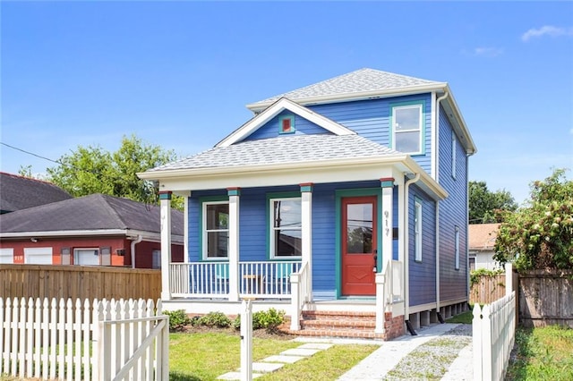 view of front of property featuring covered porch, a shingled roof, and fence