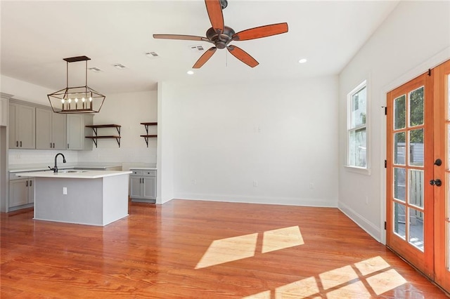 kitchen with an island with sink, light hardwood / wood-style flooring, ceiling fan, and gray cabinets