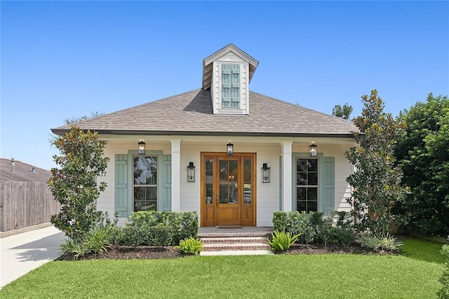 view of front of property featuring a porch, roof with shingles, fence, and a front lawn