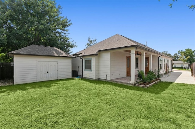 back of house with a storage shed, ceiling fan, a lawn, and an outbuilding