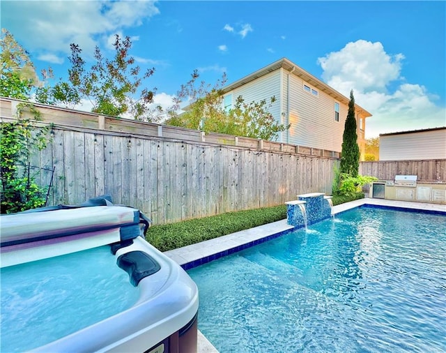 view of pool featuring pool water feature, exterior kitchen, and grilling area