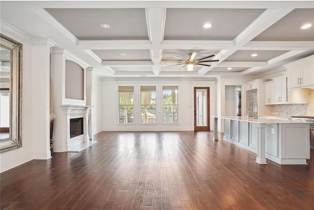 unfurnished living room with ornamental molding, coffered ceiling, ceiling fan, dark wood-type flooring, and beam ceiling