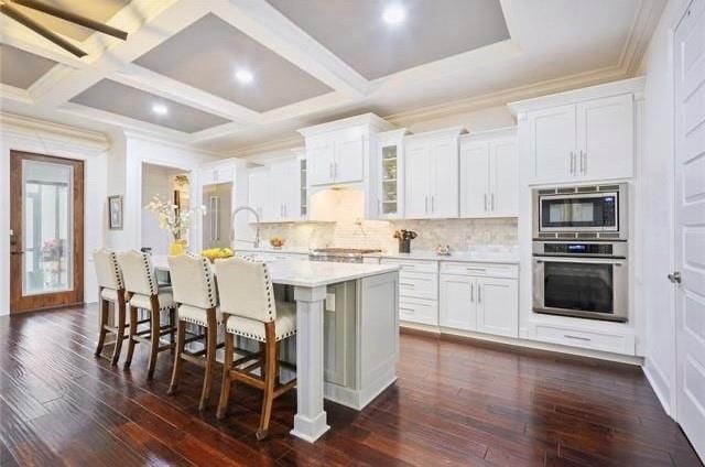 kitchen featuring white cabinetry, a kitchen island with sink, dark wood-type flooring, and stainless steel appliances