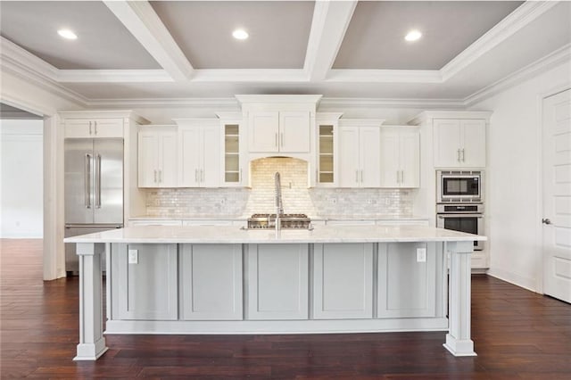 kitchen with built in appliances, dark hardwood / wood-style floors, a spacious island, and white cabinets