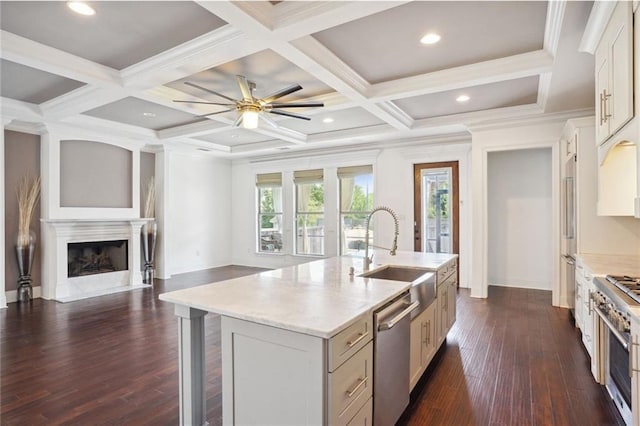 kitchen with sink, coffered ceiling, dark hardwood / wood-style floors, a fireplace, and a center island with sink