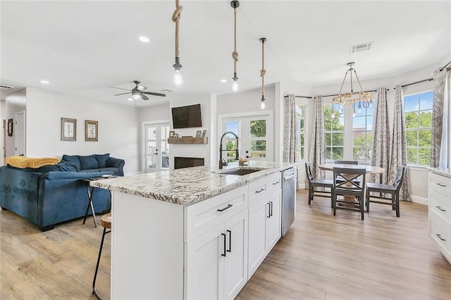 kitchen featuring ceiling fan, hanging light fixtures, sink, a center island with sink, and light hardwood / wood-style flooring