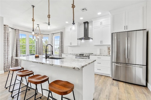 kitchen featuring a center island with sink, stainless steel appliances, sink, and wall chimney range hood