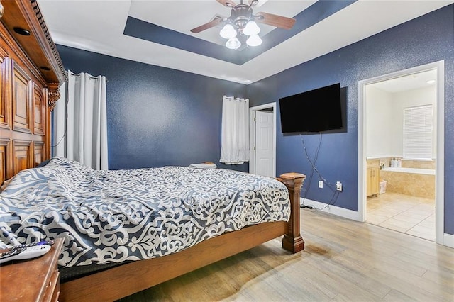 bedroom with ceiling fan, light wood-type flooring, and ensuite bath