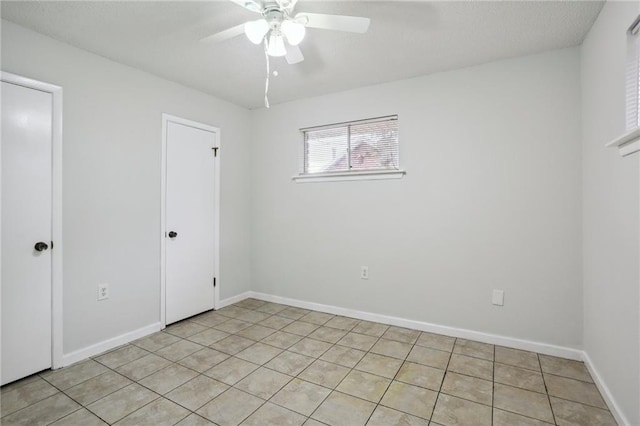 tiled spare room with ceiling fan