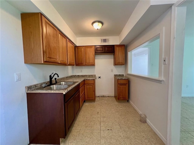 kitchen featuring light tile patterned floors, sink, and light stone countertops