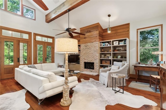 living room featuring a brick fireplace, hardwood / wood-style floors, beamed ceiling, ceiling fan, and high vaulted ceiling