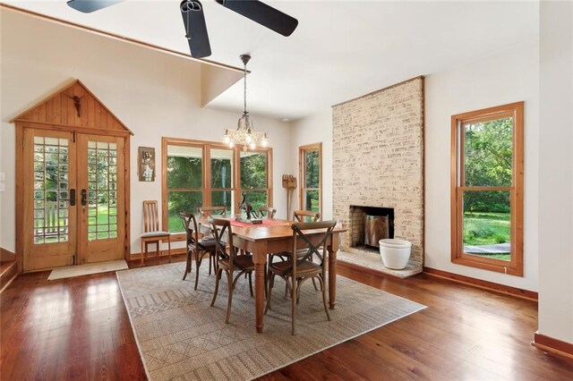 dining area featuring ceiling fan with notable chandelier, a fireplace, and dark hardwood / wood-style floors