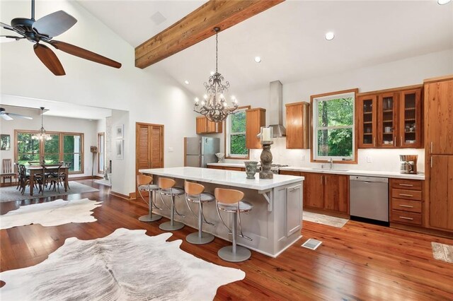 kitchen with a kitchen island, dark hardwood / wood-style floors, a kitchen breakfast bar, ceiling fan with notable chandelier, and appliances with stainless steel finishes