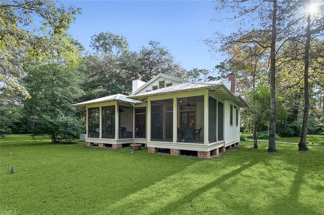 back of house featuring a lawn and a sunroom