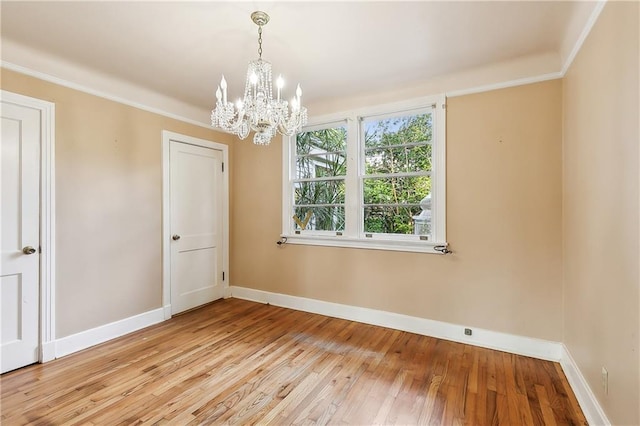 unfurnished room featuring ornamental molding, light wood-type flooring, and a notable chandelier