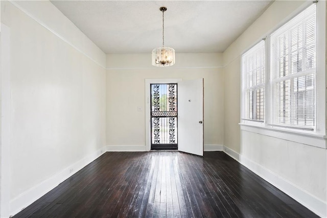 doorway featuring dark wood-type flooring and an inviting chandelier