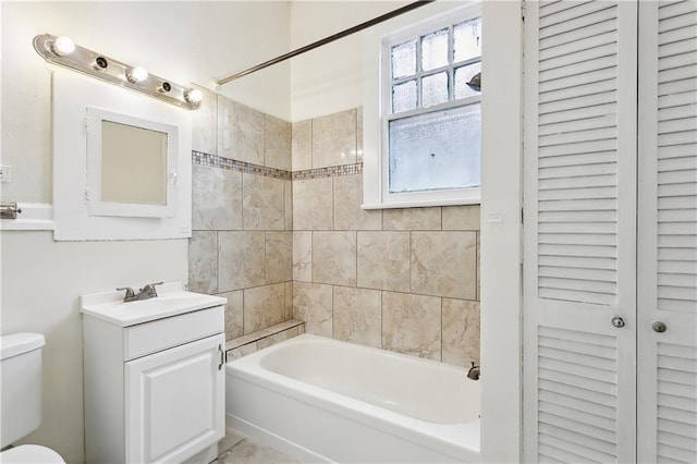 full bathroom with tiled shower / bath, vanity, and toilet