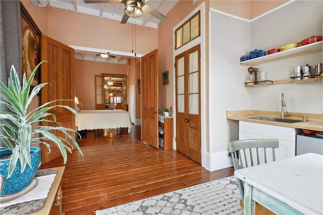 interior space featuring white cabinets, ceiling fan, hardwood / wood-style flooring, and sink