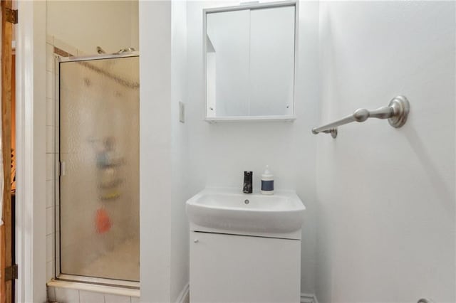 bathroom featuring a shower with door and vanity