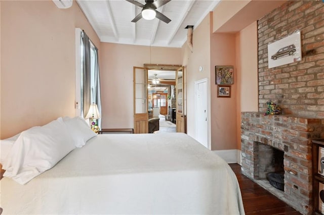 bedroom with ceiling fan, beamed ceiling, a fireplace, and dark wood-type flooring