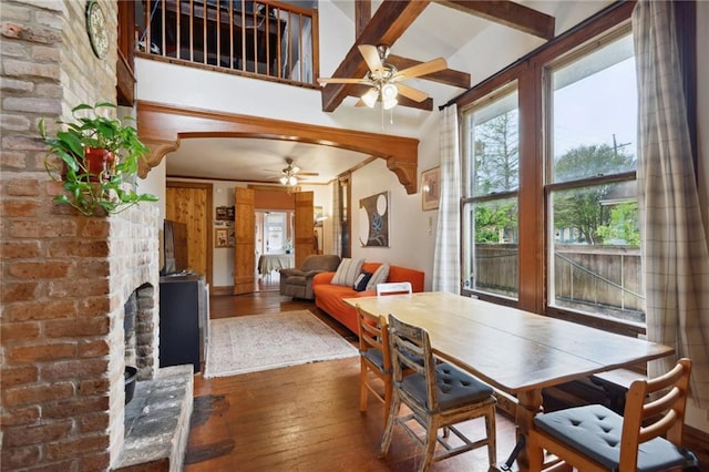 dining space with a fireplace, a towering ceiling, hardwood / wood-style floors, and ceiling fan