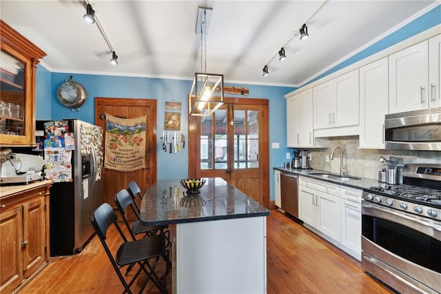 kitchen with white cabinets, a kitchen island, stainless steel appliances, light wood-type flooring, and sink